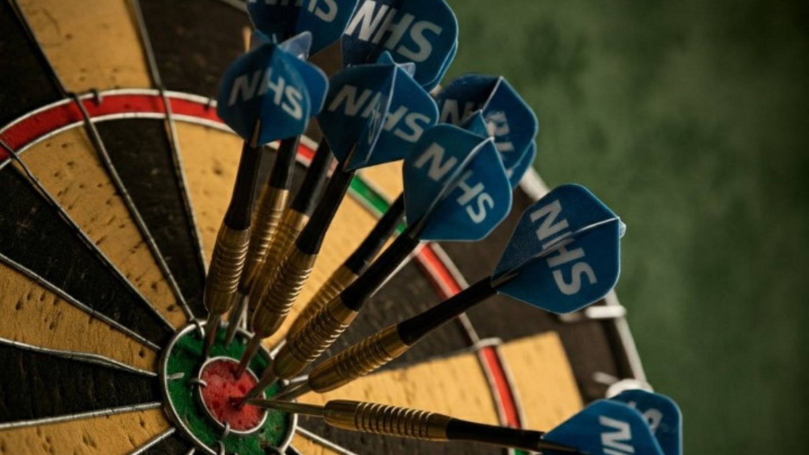 dartboard with darts with NHS logo in bullseye