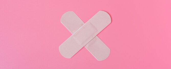 Pink background with two plasters in the middle crossing over each other. White SARD logo top right.